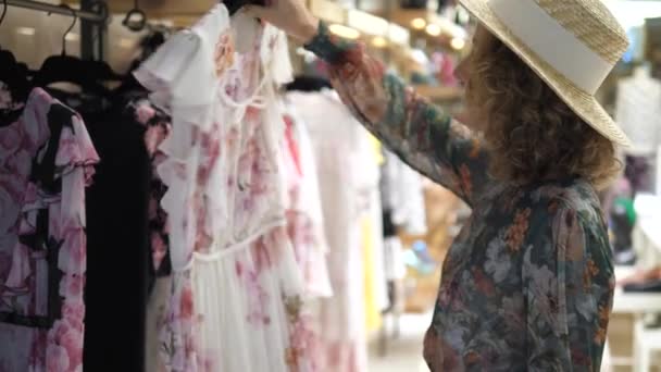 Young Woman Customer Buying Clothes At Clothing Store. Girl Choosing Floral Dress. — Stock Video