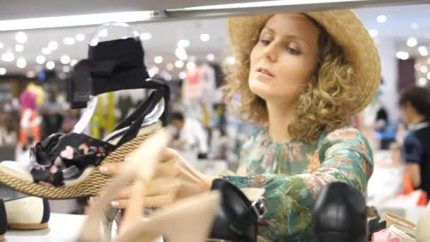 Молодая женщина выбирает обувь в магазине во время покупок — стоковое видео