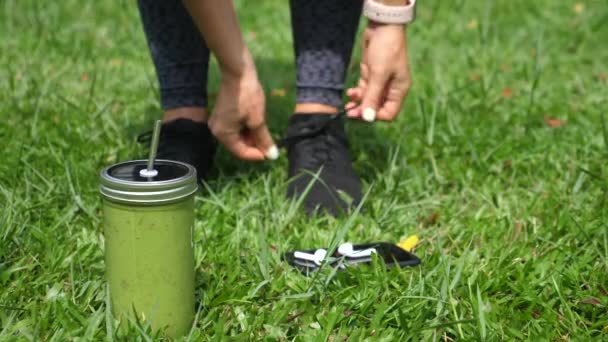 Smoothie verde, Piedi femminili che indossano scarpe sportive, Smartphone con auricolari wireless — Video Stock