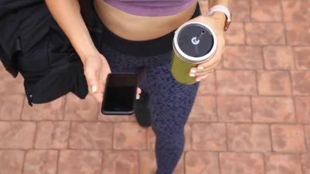 Fechar-se de jovem atleta usando telefone móvel andando ao ar livre — Vídeo de Stock