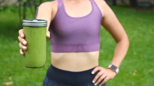 Fitnessfrau mit grünem veganen Smoothie. Konzept eines gesunden Lebensstils. — Stockvideo