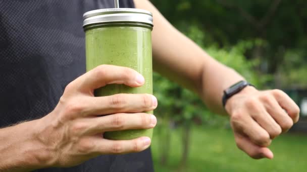 Close Up Of Young Sportsman Using Smartwatch And Holding Green Smoothie — Stock Video