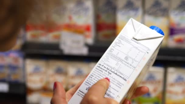 Donna che legge gli ingredienti sull'etichetta del prodotto mentre fa shopping nel supermercato. Primo piano . — Video Stock