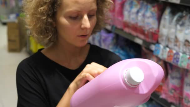 Mujer de compras en el supermercado de la etiqueta de lectura en el producto de detergente — Vídeos de Stock