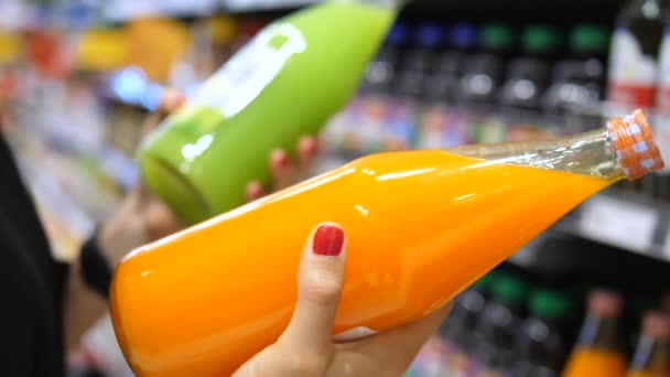 Close Up delle mani della donna La scelta di bottiglia di succo di frutta al supermercato — Video Stock
