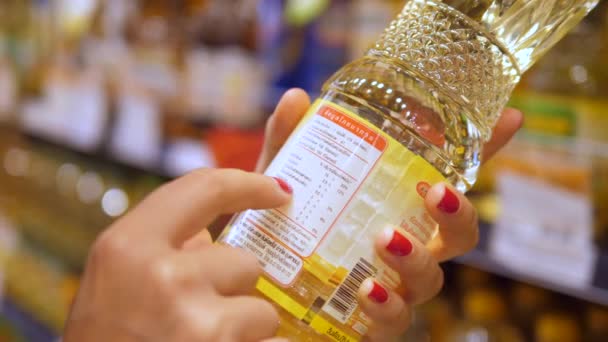 Mujer cliente lectura etiqueta en aceite de girasol en el supermercado . — Vídeo de stock