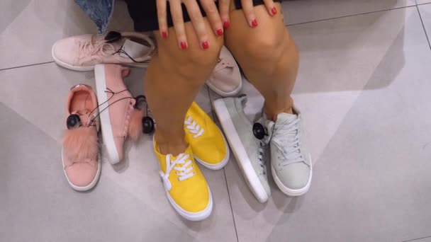 Closeup van vrouwelijke benen proberen op sneakers of trainers bij schoenenwinkel — Stockvideo