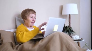 teknoloji, yaş, jest, iletişim ve insan kavramı - evde görüntülü sohbet sahip ve el sallayarak dizüstü bilgisayar ile mutlu kadın kıdemli