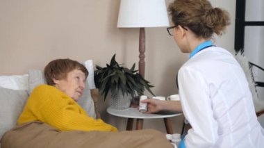 Ev ziyareti sırasında kıdemli hastaya ilaç yazan kadın doktor..