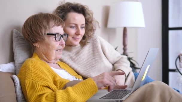 Abuela y nieta usando ordenador portátil juntos en casa — Vídeos de Stock