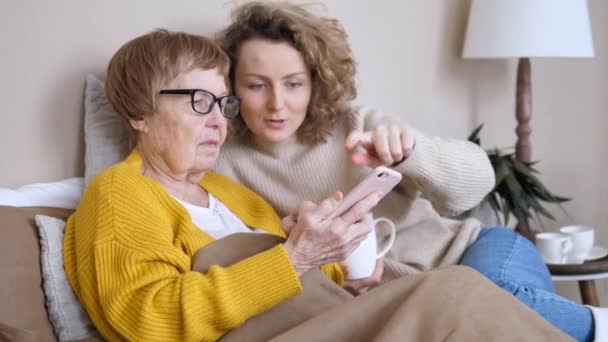 Barnbarn lära mormor hur man använder smartphone hemma — Stockvideo