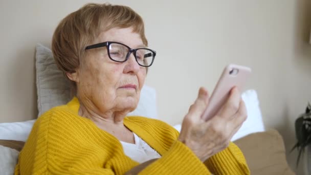 Портрет пожилой пенсионерки со смартфоном дома . — стоковое видео