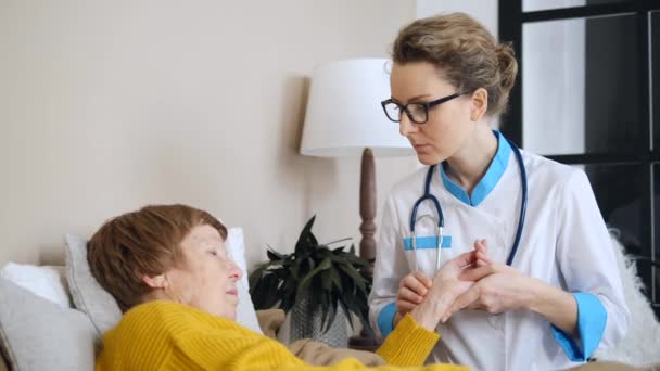 Γυναίκα γιατρός Εξετάζει τον σφυγμό των ηλικιωμένων ασθενών. Έννοια φροντίδας και βοήθειας ηλικιωμένων. — Αρχείο Βίντεο
