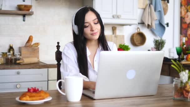 Jovem mulher trabalhando no computador portátil na cozinha em casa — Vídeo de Stock