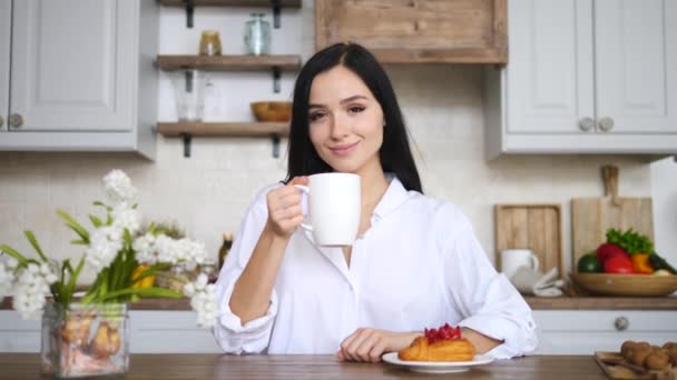 좋은 아침 컨셉이야. 주방에서 커피를 마시며 웃고 있는 젊은 여자의 사진 — 비디오
