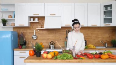 Genç Esmer Kadın Mutfakta Yemek Yapıyor Sağlıklı Salata Yapıyor Kulaklıkla Dans Ediyor.