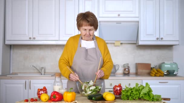 Старшая женщина готовит салат на кухне. Концепция здорового образа жизни . — стоковое видео