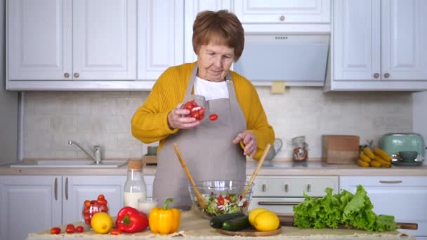 Senior vrouw die salade kookt in de keuken. Gezond eten concept. — Stockvideo