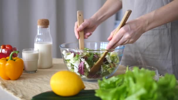 Großaufnahme weiblicher Hände, die in der Küche grünen Salat in einer Schüssel mischen. — Stockvideo