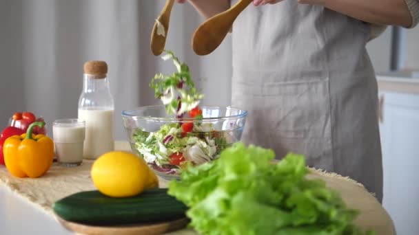 Konzept einer gesunden vegetarischen und veganen Ernährung. Frau mixt Salat in Küche. — Stockvideo
