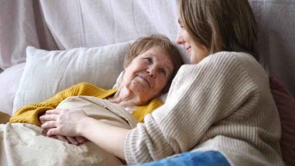 Nieta Apoyando y animando a la abuela en la cama sosteniendo su mano . — Vídeos de Stock