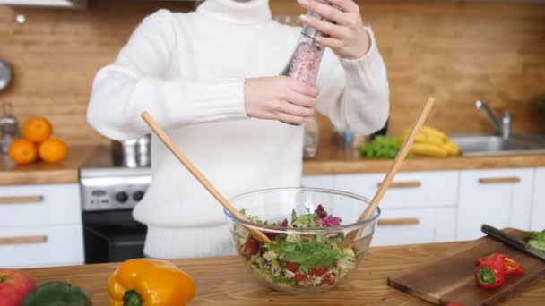 Donna che prepara insalata sana in cucina, aggiungendo sale alla ciotola . — Video Stock