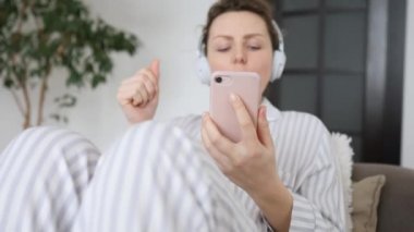Halk ve Teknoloji Konsepti. Kulaklıkla Müzikten Hoşlanan Kadın Cep Telefonu Kullanıyor.