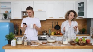 Mutfakta cep telefonu kullanan genç bir çift. Teknolojiye Takıntı.