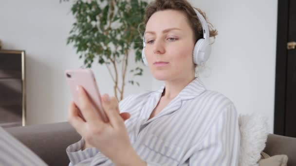 Mujer joven con auriculares usando Smartphone en casa . — Vídeo de stock