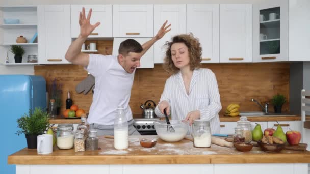 Casal jovem feliz se divertindo na cozinha. Homem Truques e Pranks Mulher assustada . — Vídeo de Stock