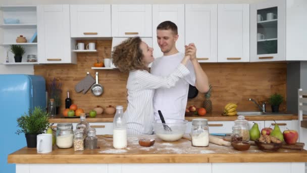 Jong paar verliefd dansen in keuken thuis tijdens het koken ontbijt. — Stockvideo