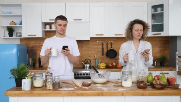 Millennial casal obcecado com smartphones ignorando uns aos outros na cozinha . — Vídeo de Stock