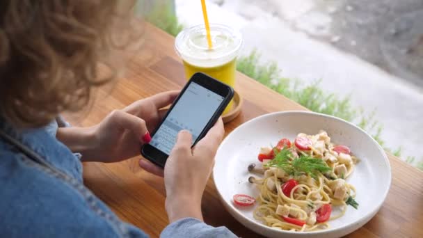 Kvinna som använder mobiltelefon medan du äter middag på hälsosam Vegansk restaurang — Stockvideo