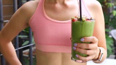 Yeşil Vejetaryen Meyve Smoothie 'sini tutan ve başparmaklarını gösteren spor kadını. Sağlıklı Yaşam Tarzı.