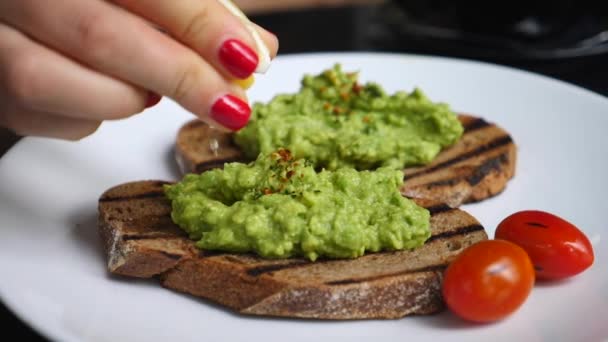 Woman Hand Squirts Lemon Juice Over Avocado Toast — Stock Video