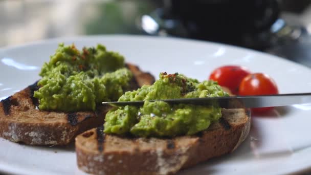 Püresi avokado ekmek üzerine yayılıyor. Sağlıklı vejetaryen Kahvaltı. — Stok video