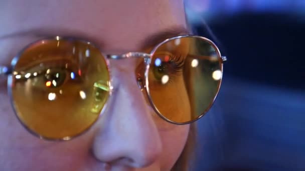 Primer plano de los ojos femeninos en gafas de sol amarillas de moda con reflección de faros de carretera nocturnos — Vídeos de Stock