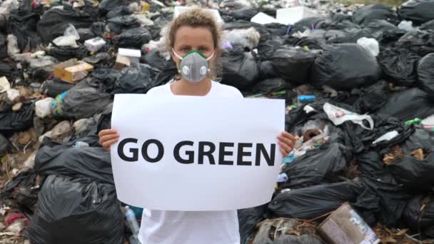 Egy nő, aki a "Go Green" posztert tartja a szemétlerakón. Újrahasznosítás, öko, újrahasznosítási koncepció. — Stock videók