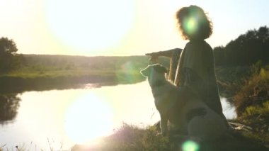 Nehir kenarındaki Köpek Arkadaşı ile Kız Gün batımında Vahşi Doğanın tadını çıkarıyor