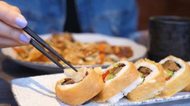 Japon restoranında Ginger 'ı yemek çubuklarıyla suşi setine koyan kadın eli..