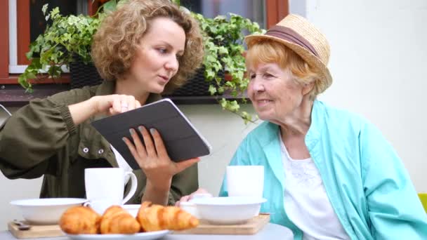 Внучка и бабушка используют планшет в кафе — стоковое видео