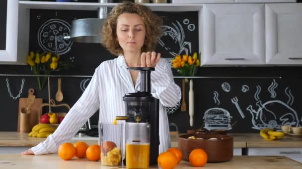 Kvinnan klämmer apelsinjuice i köket på morgonen — Stockvideo