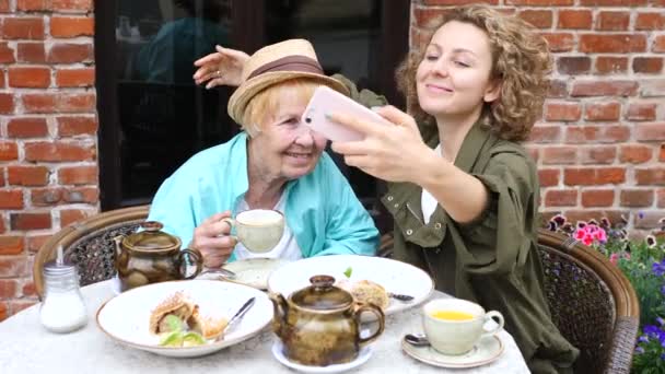 Бабуся і внучка роблять сельфі зі смартфоном у кафе — стокове відео