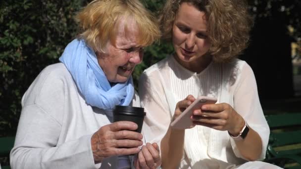 Концепция людей и технологий. Бабушка и внучка с помощью смартфона . — стоковое видео
