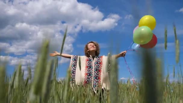 Молодая женщина размахивает руками с шариками в поле — стоковое видео