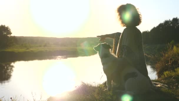 Flicka med hund vän på stranden njuter av vild natur vid solnedgången — Stockvideo