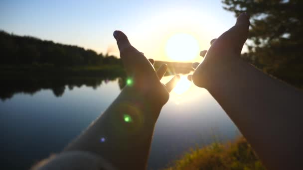 Mãos femininas alcançando o sol ao pôr do sol em Riverside — Vídeo de Stock