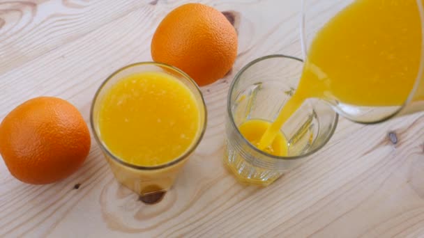 Gros plan de jus d'orange frais dans le verre sur la table en bois — Video