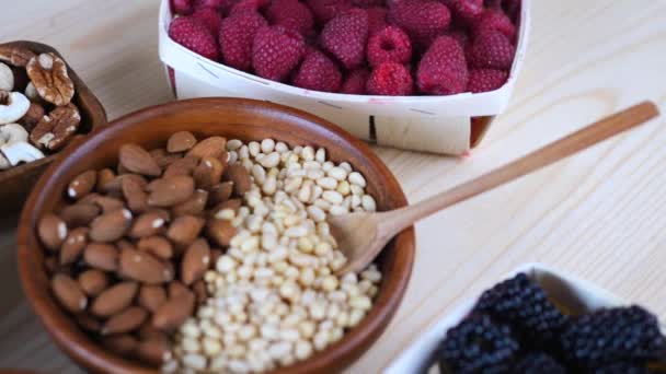 Gezond eten concept. Sluiten van noten en bessen op houten tafel. — Stockvideo