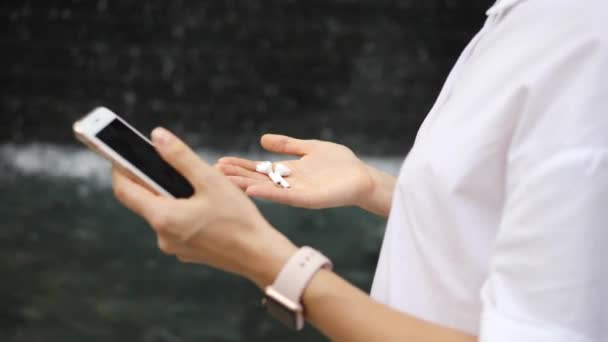 Женские руки с помощью смартфона, смартфонов и воздушных капсул, соединенных вместе — стоковое видео